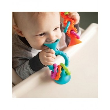 PipSquigz Loops mėlynas lipšniukas - barškutis kūdikiams - vaizdas prilipinto prie stalo ir kramtantis berniukas