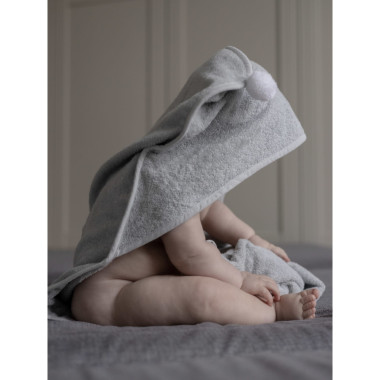 Sėdintis vaikas su vaikišku rankšluosčiu su gobtuvu