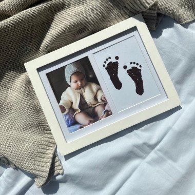 Baltas rėmelis su kūdikio nuotrauka ir rankos/pėdos spaudu