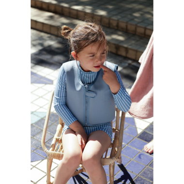 Sėdinti mergaitė su mėlynais maudymosi marškinėliais vaikams