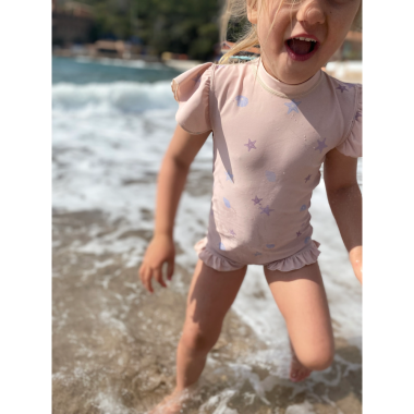 Mergaitė paplūdimyje su rausvu maudymosi kostiumėliu