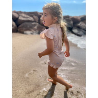 Bėganti mergaitė su rausvu maudymosi kostiumėliu