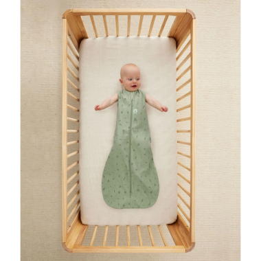 Kūdikis guli lovytėje ir dėvi ergoPouch Swaddle žalią miegmaišį 0.2TOG (8-24 mėn.)