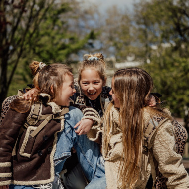 Trys mergaitės juokiasi, viena iš jų dėvi Pick & Pack vaikiška ergonominę mokyklinę kuprinę pradinukams Wild, M