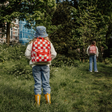 Mergaitė stovi nusisukusi ir dėvi Pick & Pack kuprinę pradinukams Raudoni langeliai, M