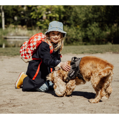 Mergaitė žaidžia su šuniuku ir dėvi Pick & Pack kuprinę pradinukams Raudoni langeliai, M
