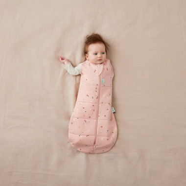 ergoPouch Swaddle miegmaišis kūdikiui 2.5TOG (6-12 mėn.) su vaiku, kuris iškišęs vieną rankytę