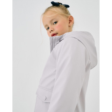 Mergaitė stovinti priekiu ir dėvinti Zippy alyvinę lietaus striukę