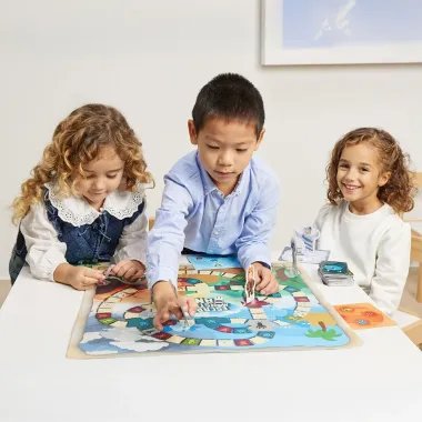 Miniland stalo žaidimas Pabėgimas iš Monstrolandijos ir žaidžiančių mergaičių bei berniuko vaizdas