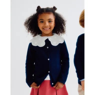 Tamsiai mėlynas užsegamas megztukas mergaitėms (3/4-13/14 m) ir jį dėvinti besišypsanti mergaitė