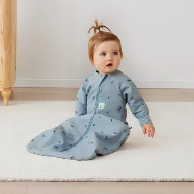 ergoPouch miegmaišis su rankovėmis kūdikiui 1.0TOG (8-24 mėn.) ir sėdinti mergaitė