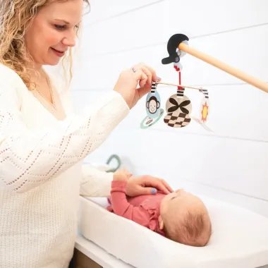 Wimmer Stim To Go kelioninė karuselė kūdikiams - žaidžianti mama su naujagimiu