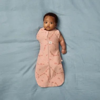 ergoPouch Swaddle miegmaišis kūdikiui 1.0TOG (0-3 mėn.) - vaikas gulintis ant mėlynos paklodės