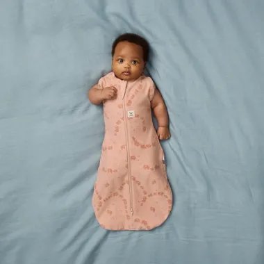 ergoPouch Swaddle miegmaišis kūdikiui 1.0TOG (0-3 mėn.) - kūdikis guli ant mėlynos paklodės su iškištomis rankomis