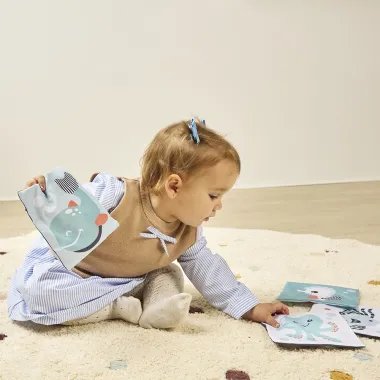 Mergaitė dėlioja minkštas kontrastingas korteles kūdikiams nuo 0 mėn.