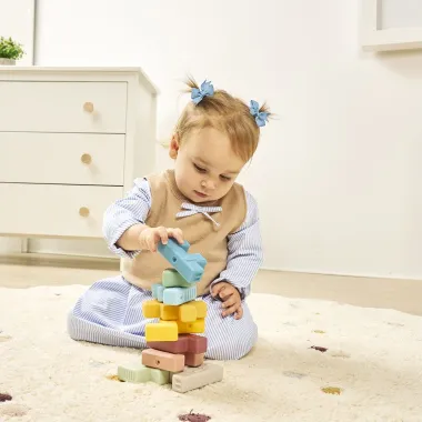 Kūdikis žaidžia su gyvūnų formų Miniland dėlione ir stato bokštą