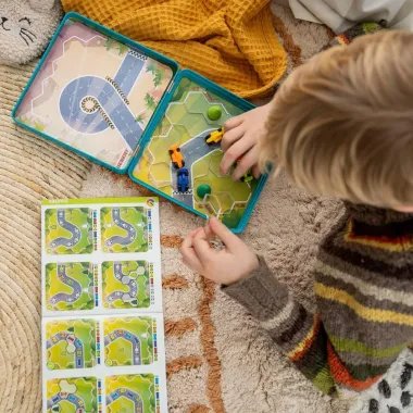 Berniukas dėlioja loginio žaidimo su lenktyninėmis mašinytėmis detales