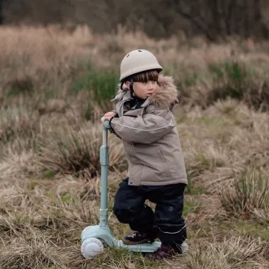 Vaikas šalia pirmojo paspirtuko su trim ratais