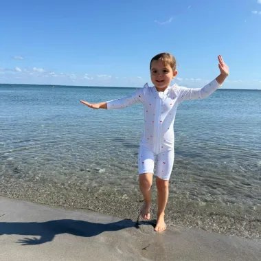 Mergaitė paplūdimyje šoka su Vanilla Copanhagen maudymuku su širdelėmis