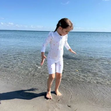 Mergaitė paplūdimyje su Vanilla Copanhagen maudymuku su širdelėmis, su UPF 50+