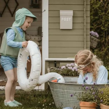 Berniukas dėvi maudymosi žalsvą kepurę ir žaidžia su mergaite