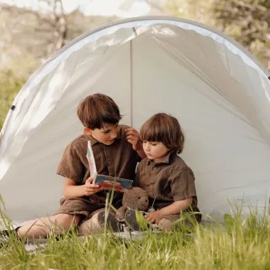Mergaitė ir berniukas sėdi pop-up rusvoje palapinėje